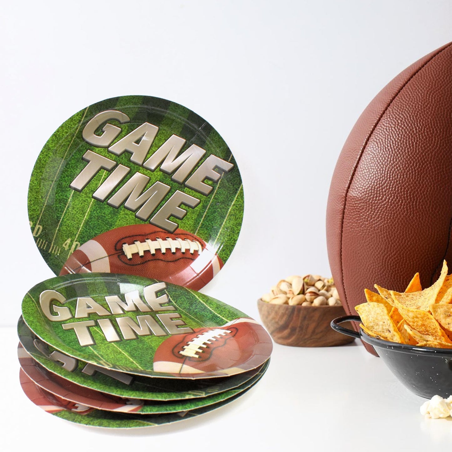 Arrangement of colorful round disposable paper plates with football and space themes on a party table.
