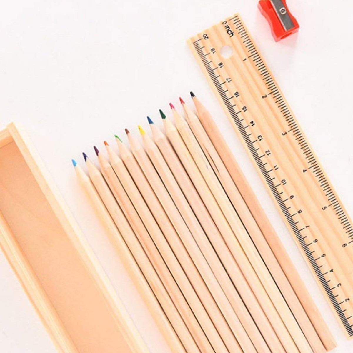 An overhead view of the wooden pencil box, 12 colored pencils, ruler, and red sharpener on a white background.
