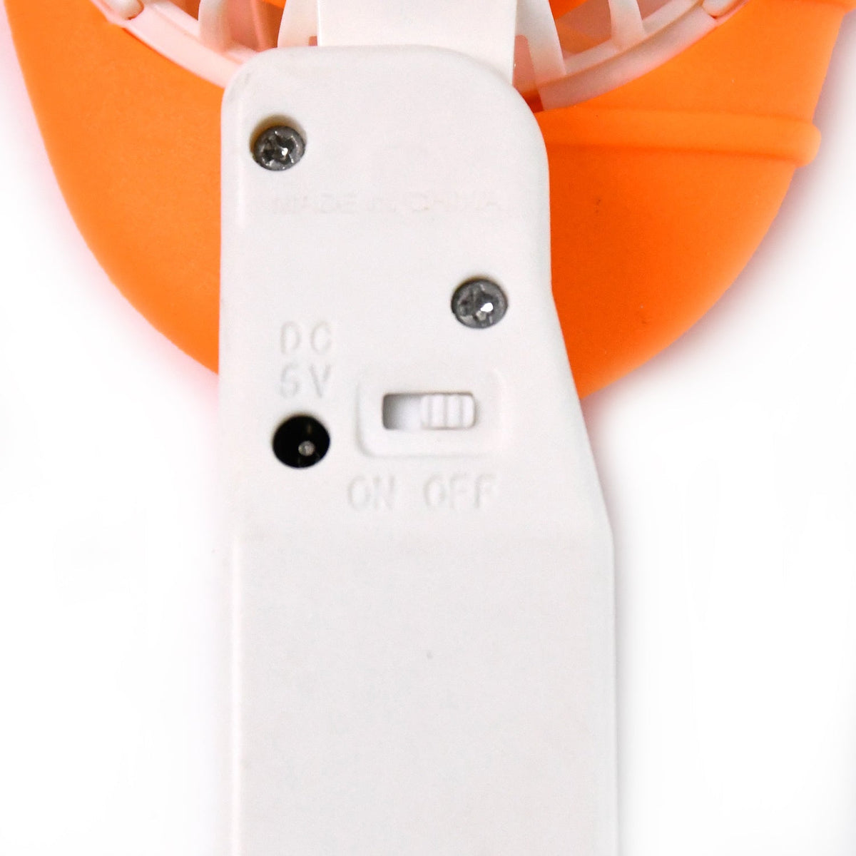 A close-up of the white handle of an orange mini fan, showing the on/off switch and charging port.