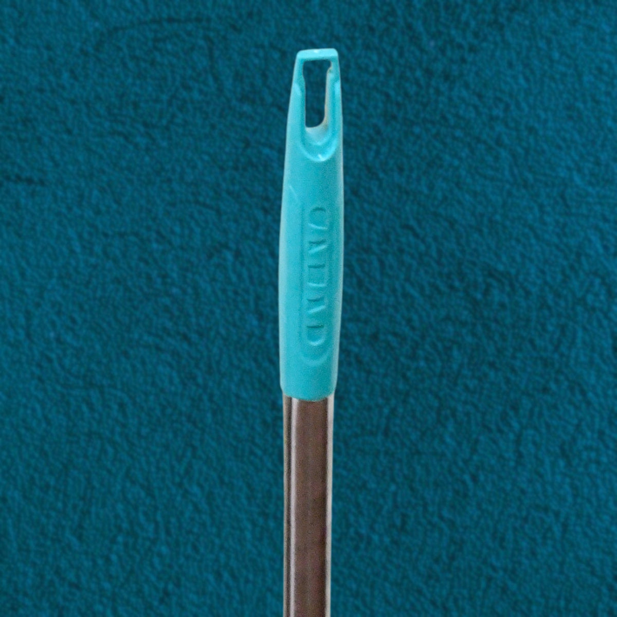 A close-up of the teal plastic handle top of a broom with a silver pole, against a teal textured background.
