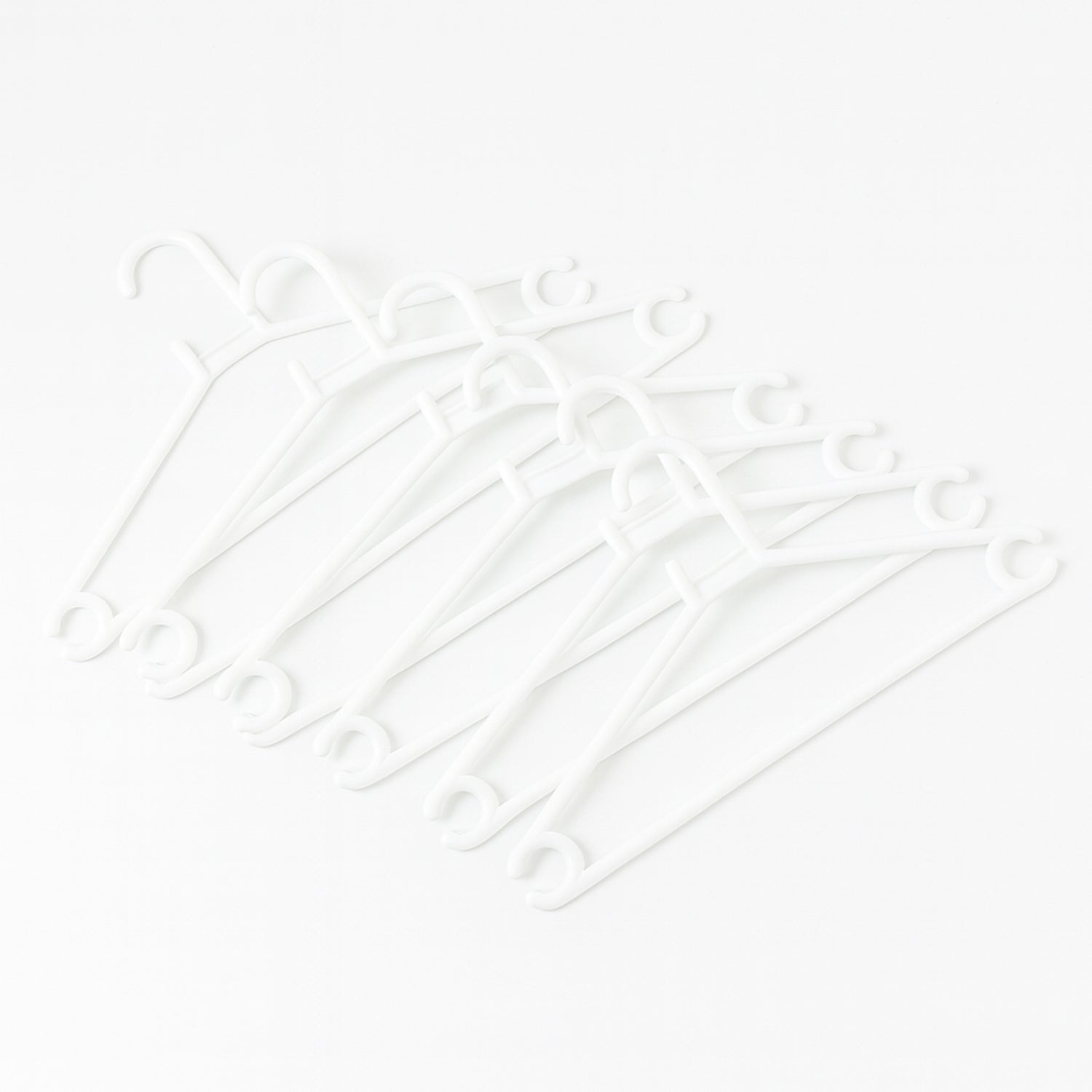 Stack of 6 white plastic clothes hangers ready for use