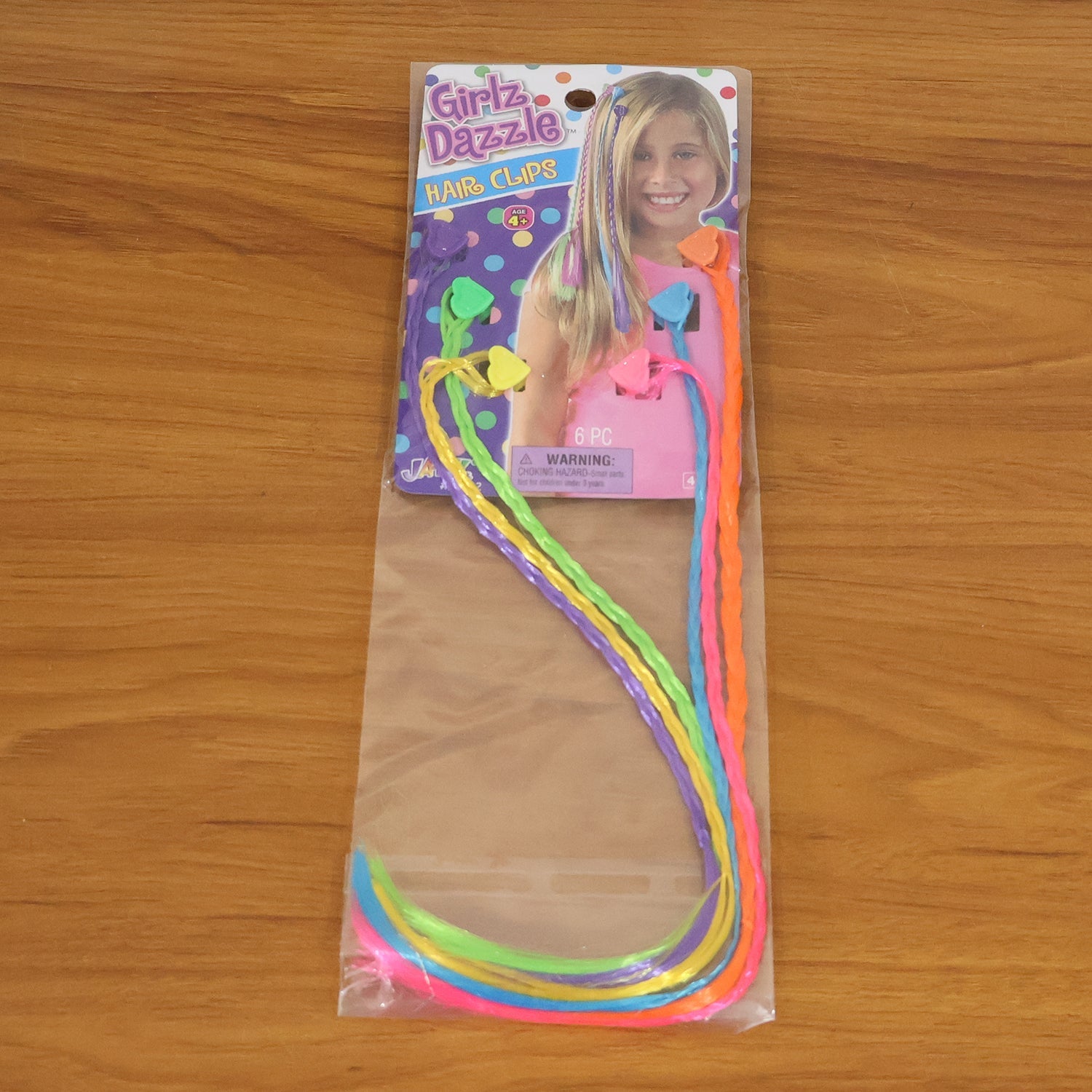Six colorful braided hair extensions are sealed in clear plastic packaging with a colorful cardboard header.