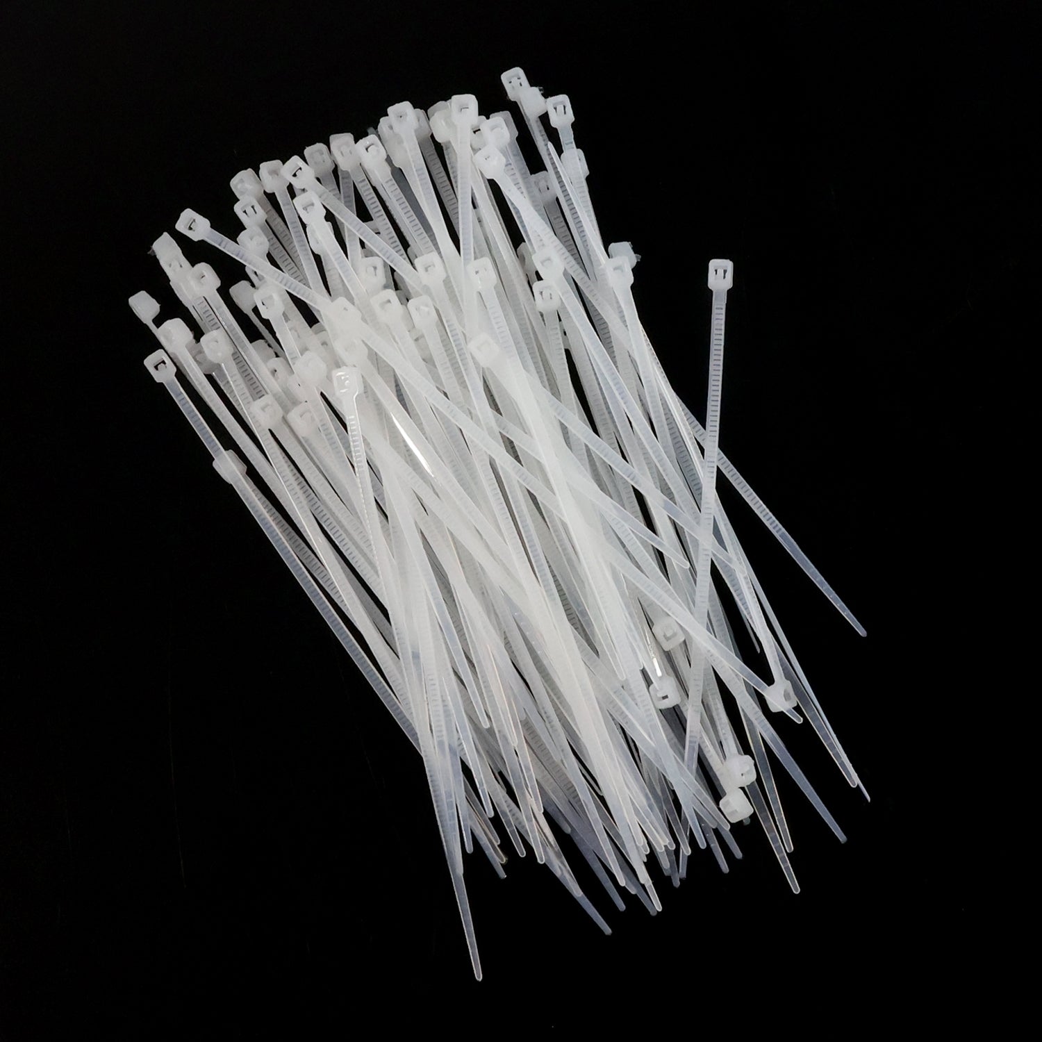 A large pile of white nylon cable ties scattered on a black background.