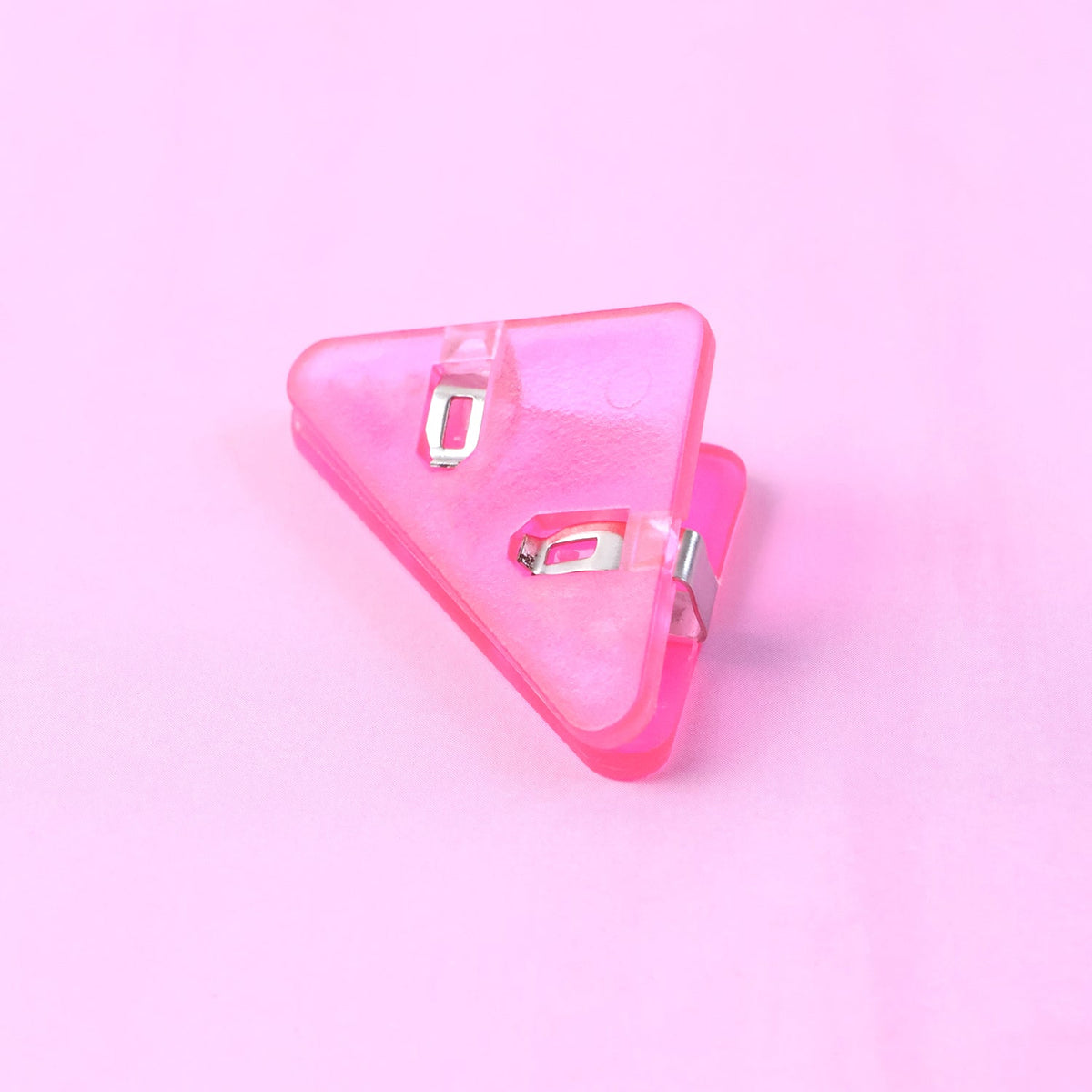 A pink plastic triangle corner clip on a solid pink background.