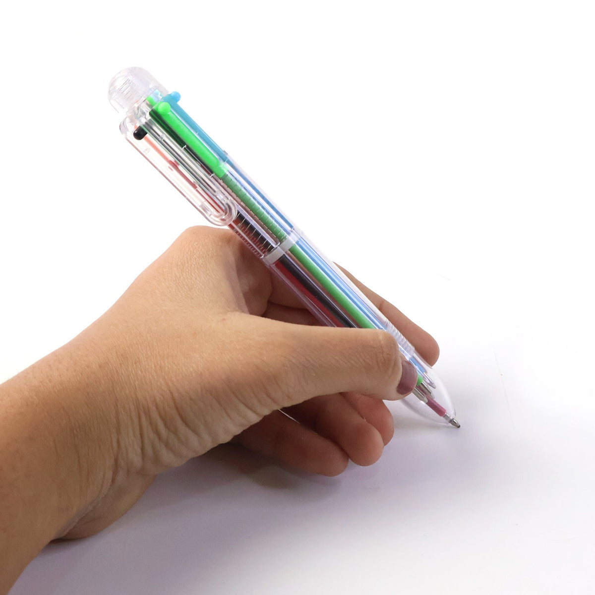 A hand holds a clear 6-in-1 multicolor ballpoint pen on a white background, with the pen angled downwards as if writing.