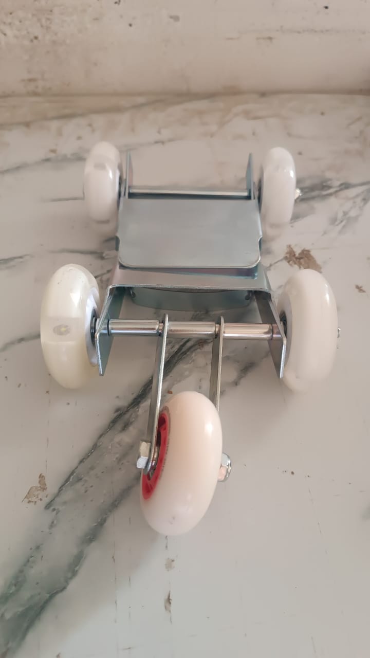 A silver metal roller stand with four white wheels and red accents is viewed from above on a marble surface.