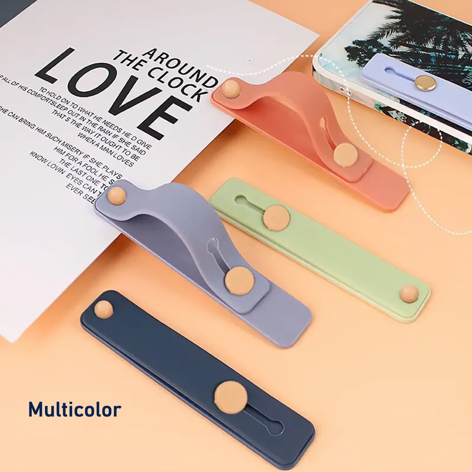 Four silicone phone grips in dark blue, light blue, green, and peach, arranged on a surface with a paper.