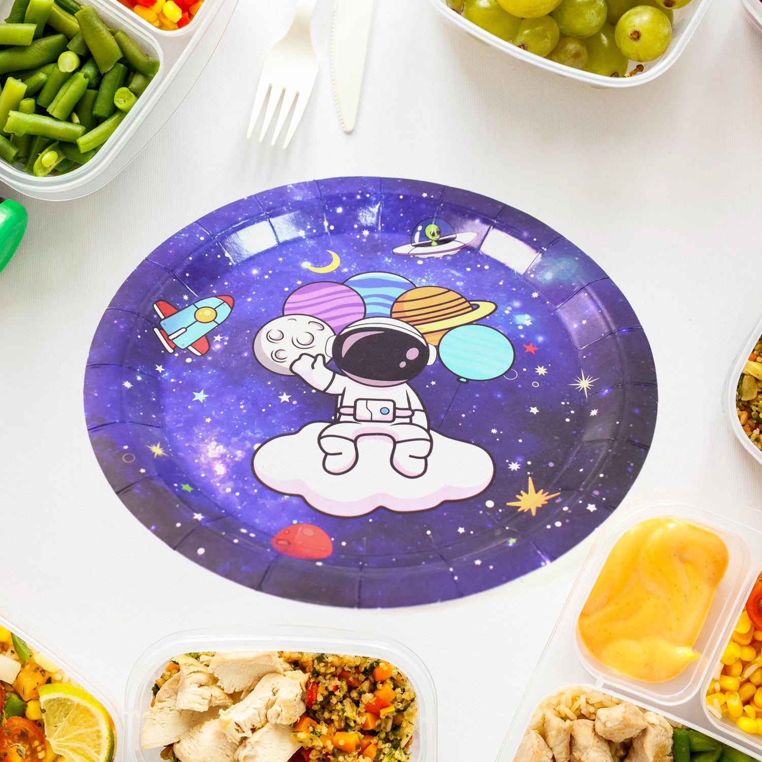 A single purple paper plate with an astronaut and planets design, surrounded by various meal prep containers.