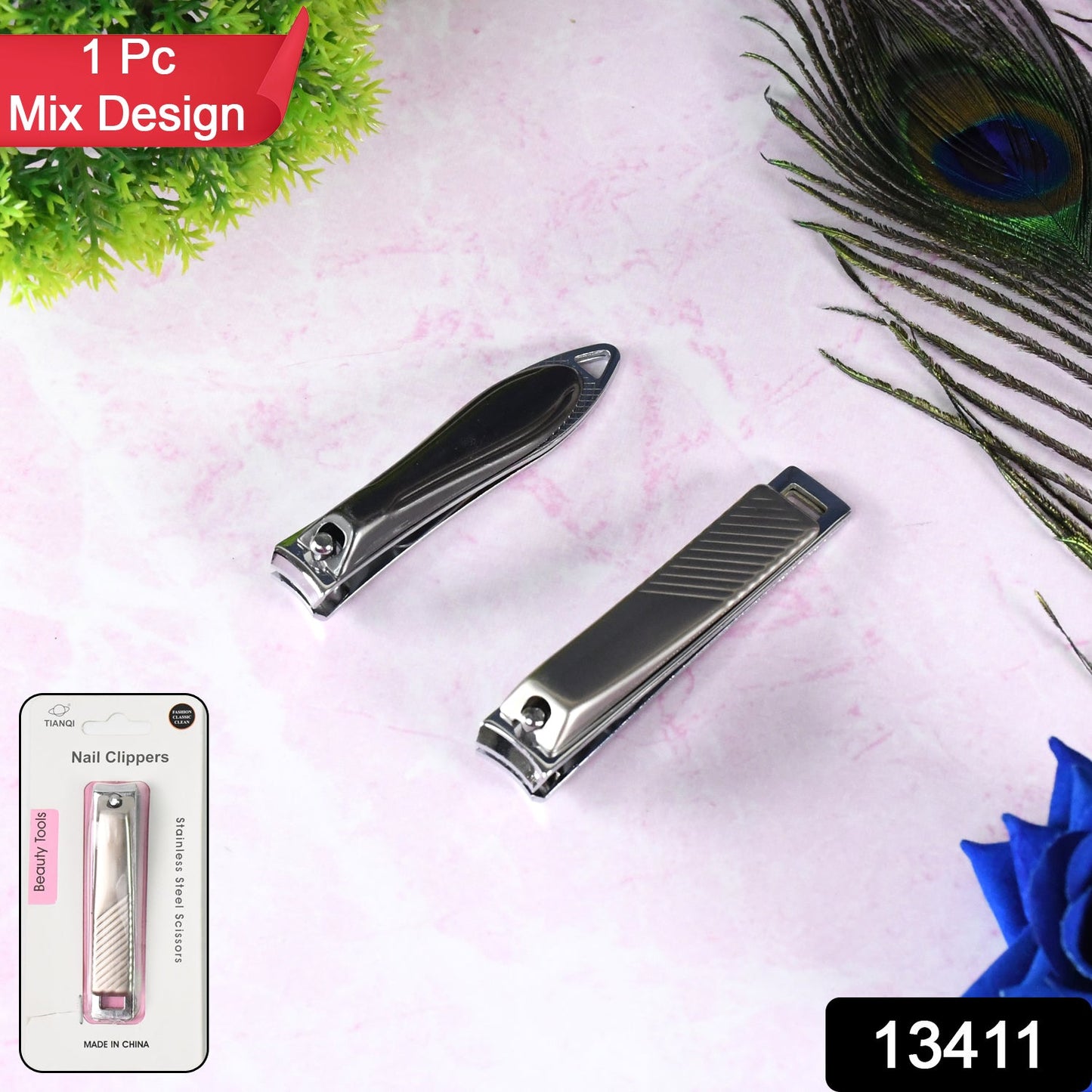 Two stainless steel nail clippers on a pink surface with a peacock feather and a blue flower.