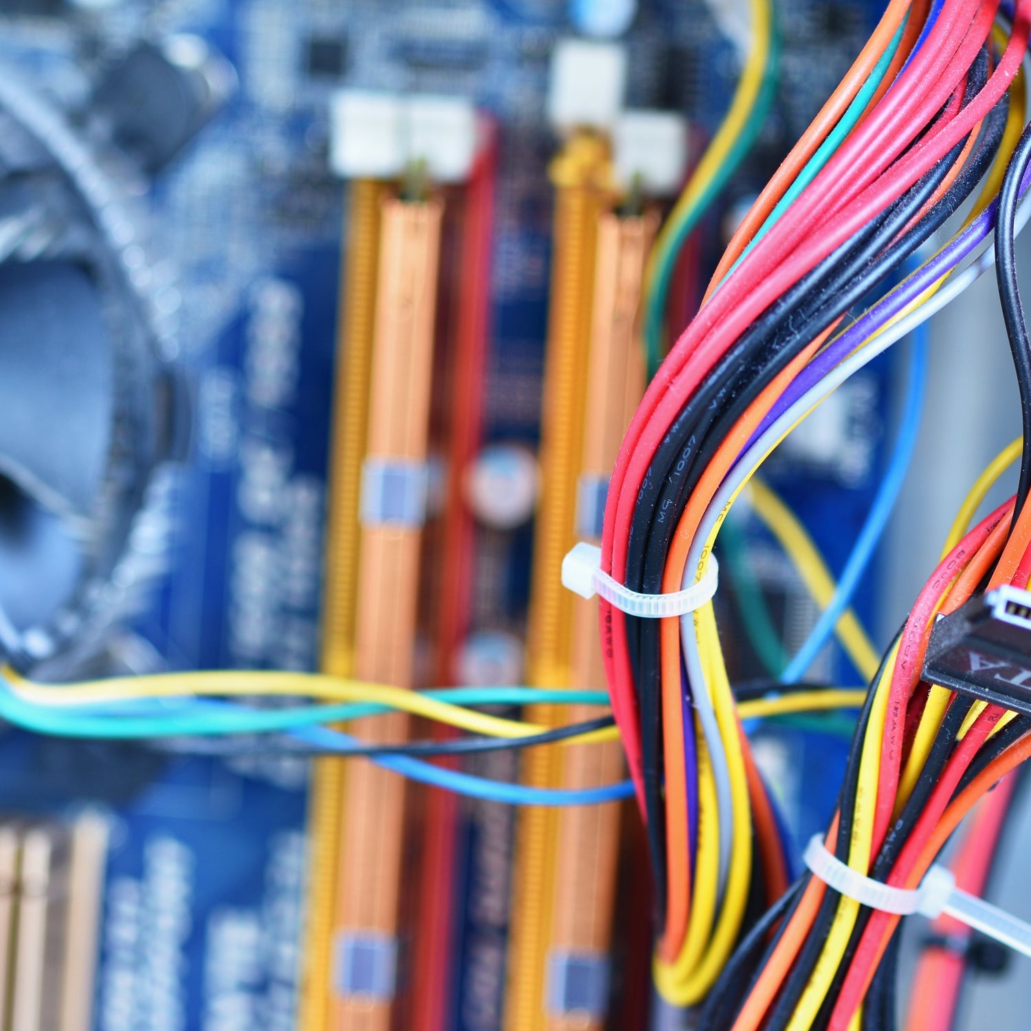 White cable ties securing bundles of colorful wires within a computer motherboard.