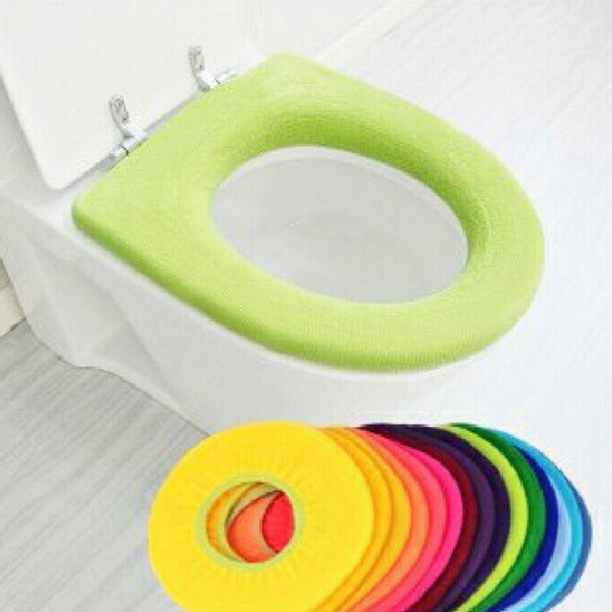 A lime green soft fabric toilet seat cover on a white toilet, with a stack of colorful covers below.