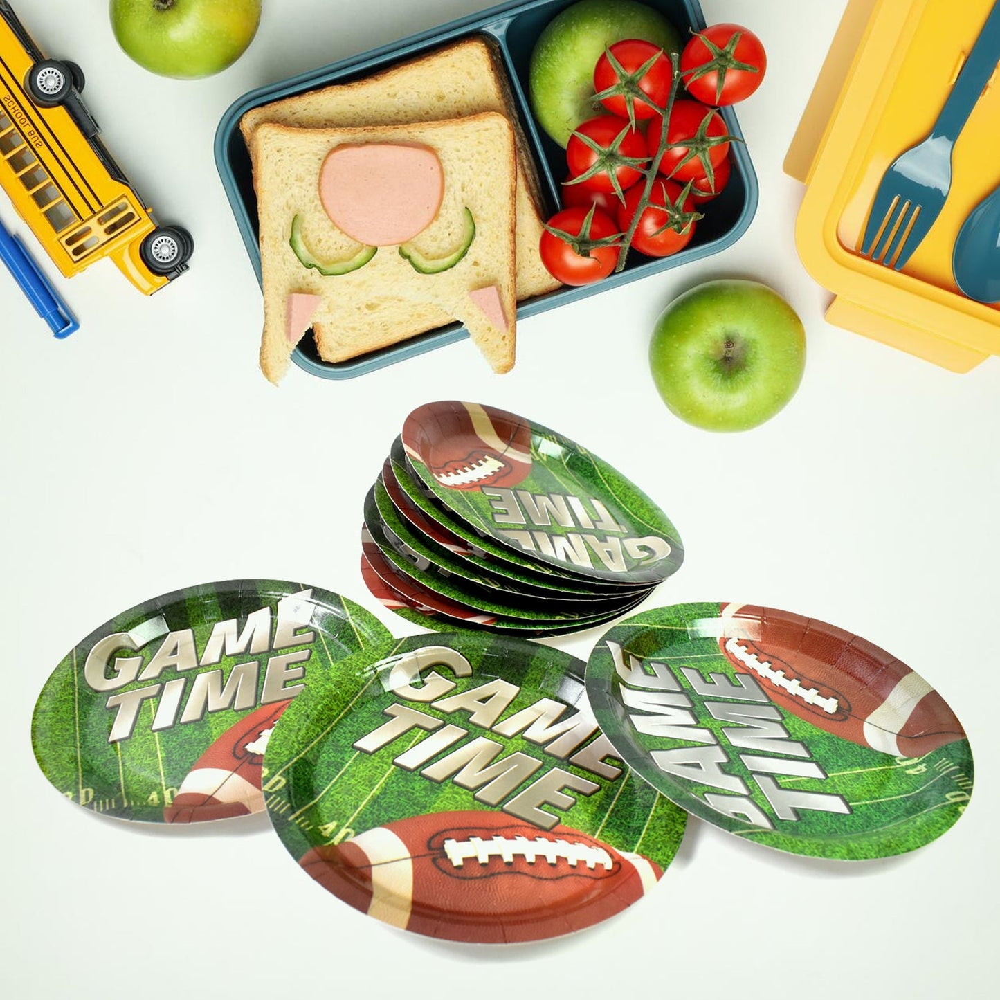 A stack of green football-themed paper plates with four individual plates, surrounded by school lunch items.