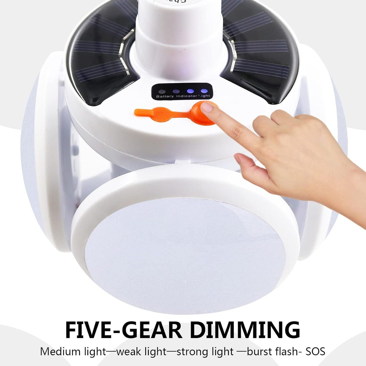 A hand presses the orange button on the white camping light, which has visible solar panels and indicator lights.