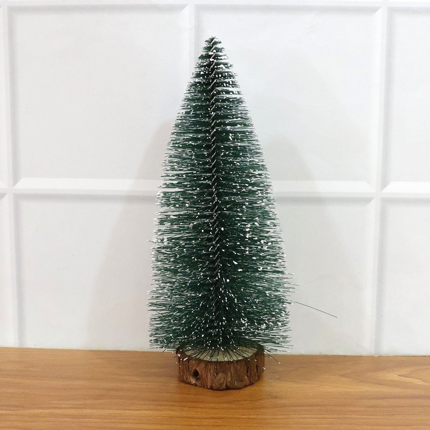 Miniature green Christmas tree with snow effect and sturdy wooden base for festive decor