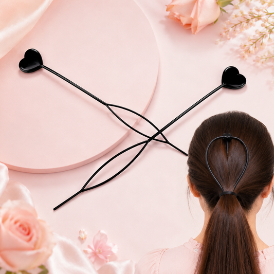 Two black heart-shaped hair styling tools on a pink surface, with one shown in use on a ponytail.