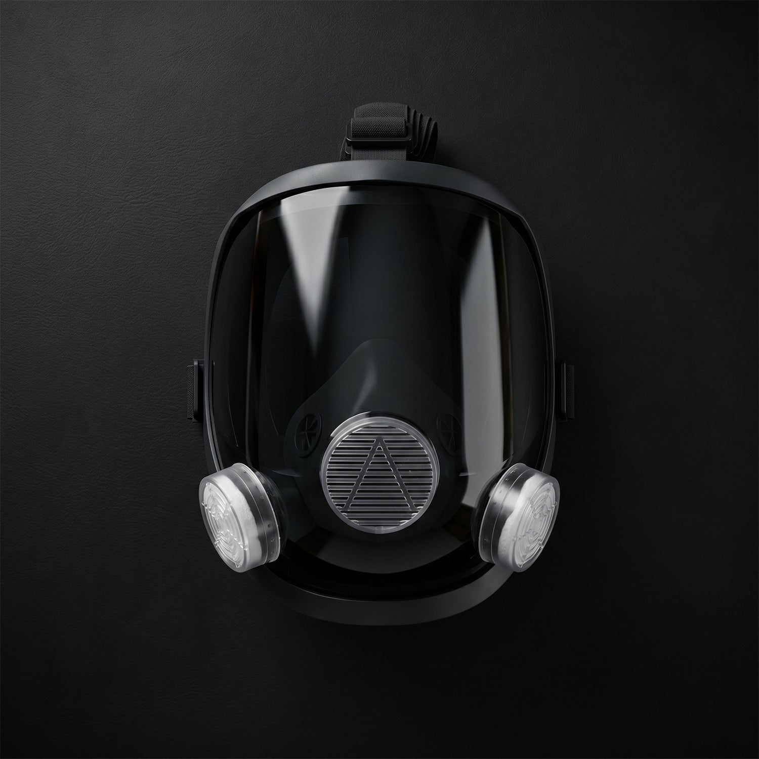 Black full face respirator mask with clear visor and two white filters, centered on a dark background.