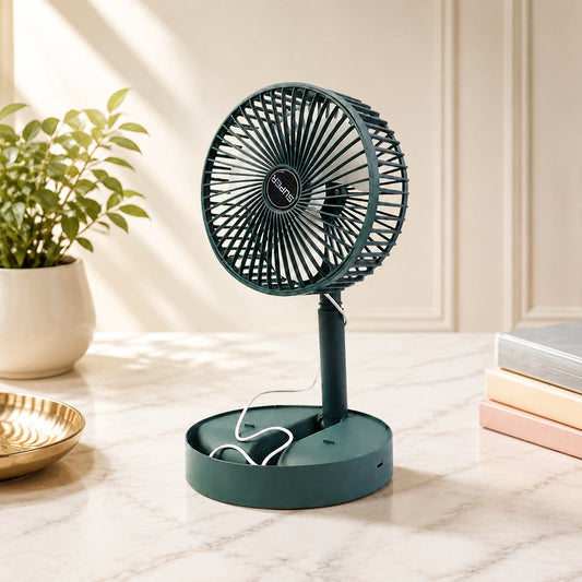 A dark green telescopic foldable mini USB desk fan on a marble desk next to a plant and books.