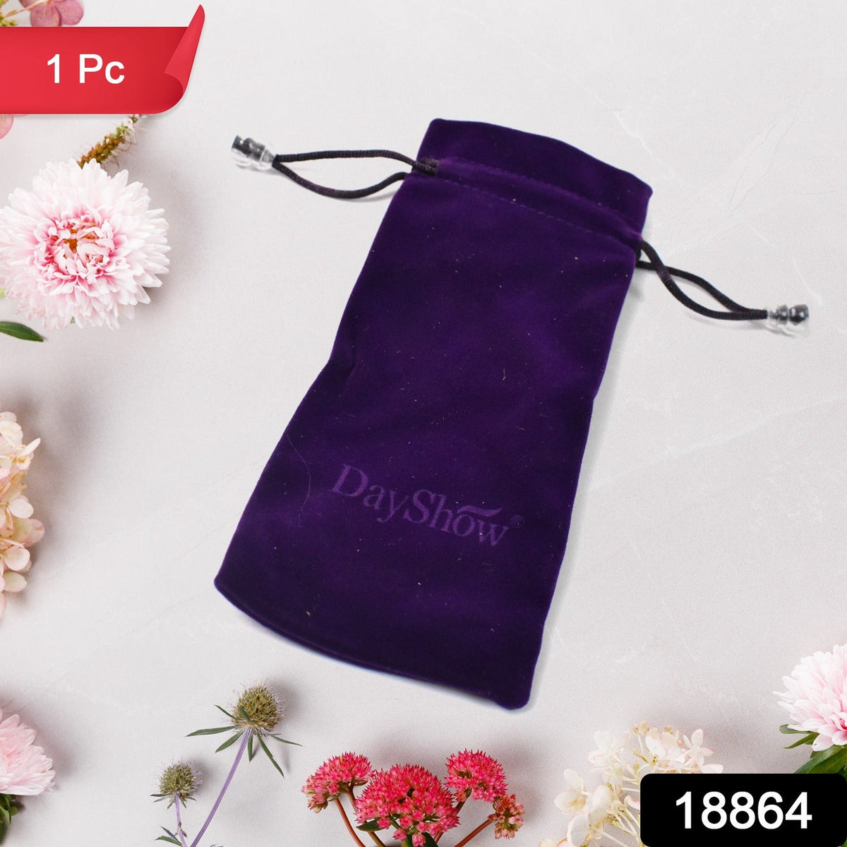 A single purple velvet drawstring bag with a DayShow logo lies on a white surface surrounded by pink and white flowers.