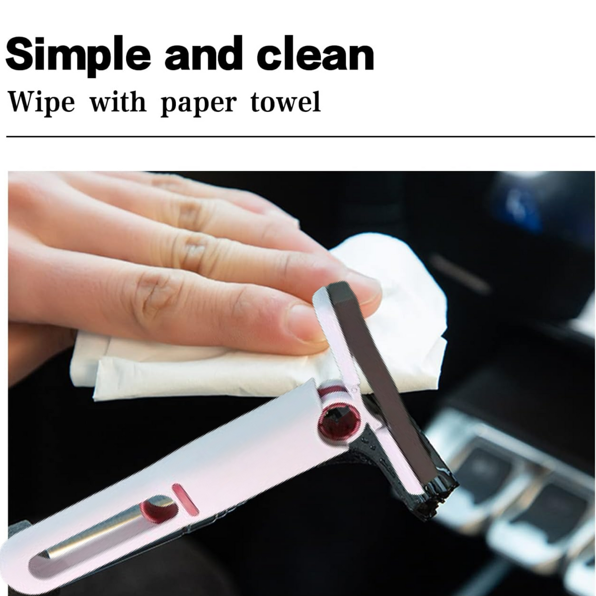 A hand uses a paper towel to clean the black brush head of the white and red silicone squeegee.