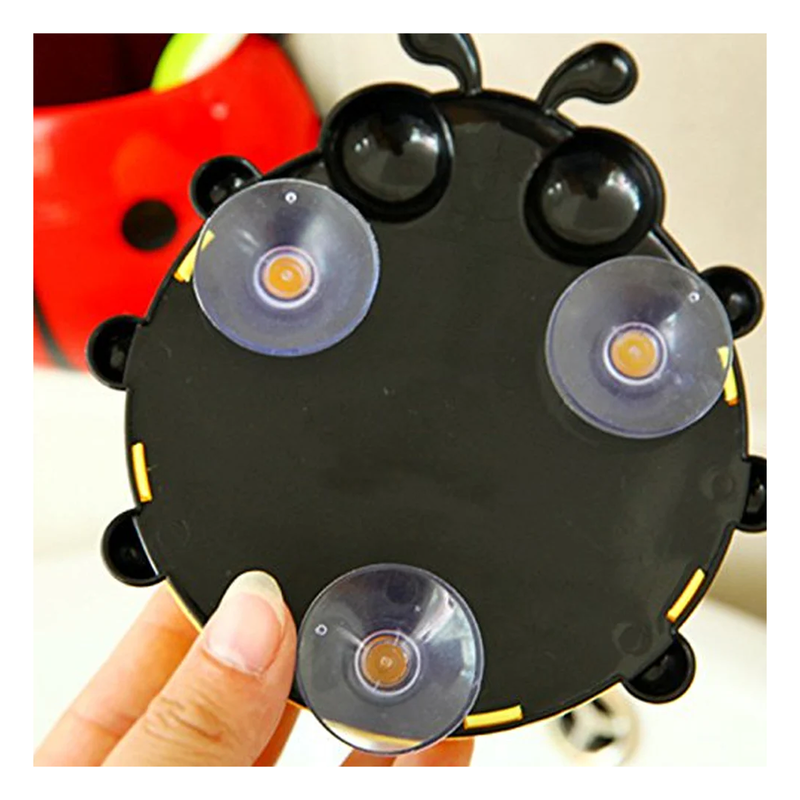 A hand holds the black back of a ladybug holder, revealing three clear suction cups with yellow centers.