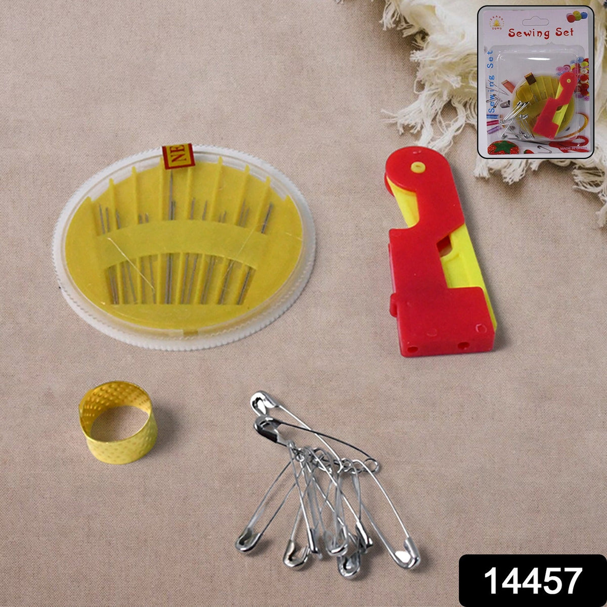 A yellow needle disc, red and yellow needle threader, gold thimble, and silver safety pins on a beige surface.