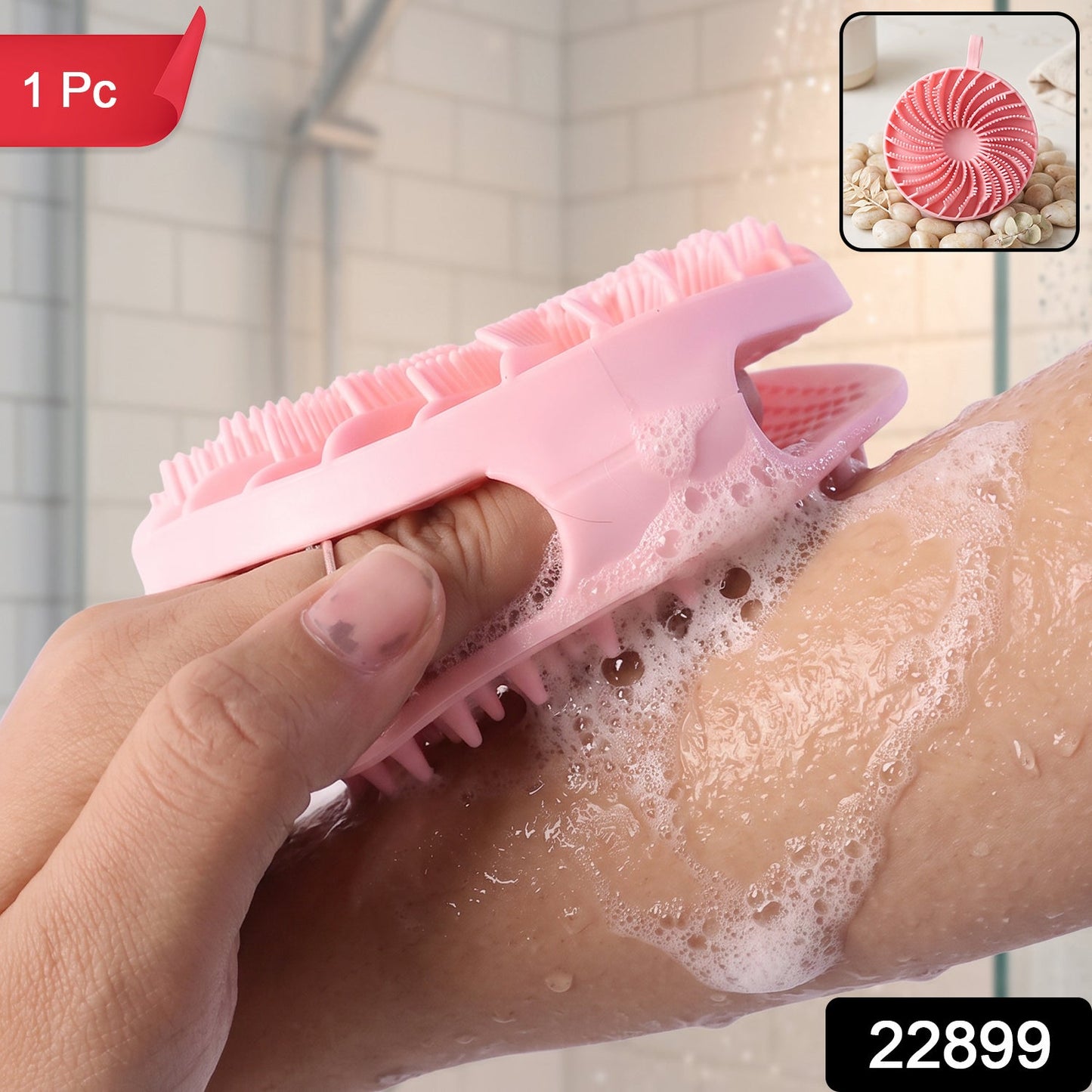 A hand holds a pink silicone body scrubber, lathering soap on an arm in a shower with a small inset image and a red '1 Pc'