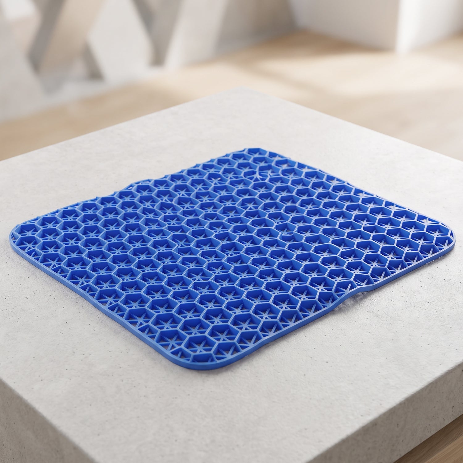 Angled view of the blue honeycomb gel cushion resting on a light gray concrete surface.