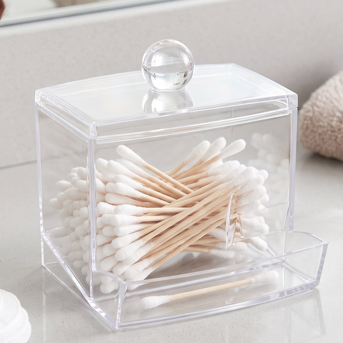 Clear acrylic cotton swab dispenser filled with cotton swabs, with a small inset image.