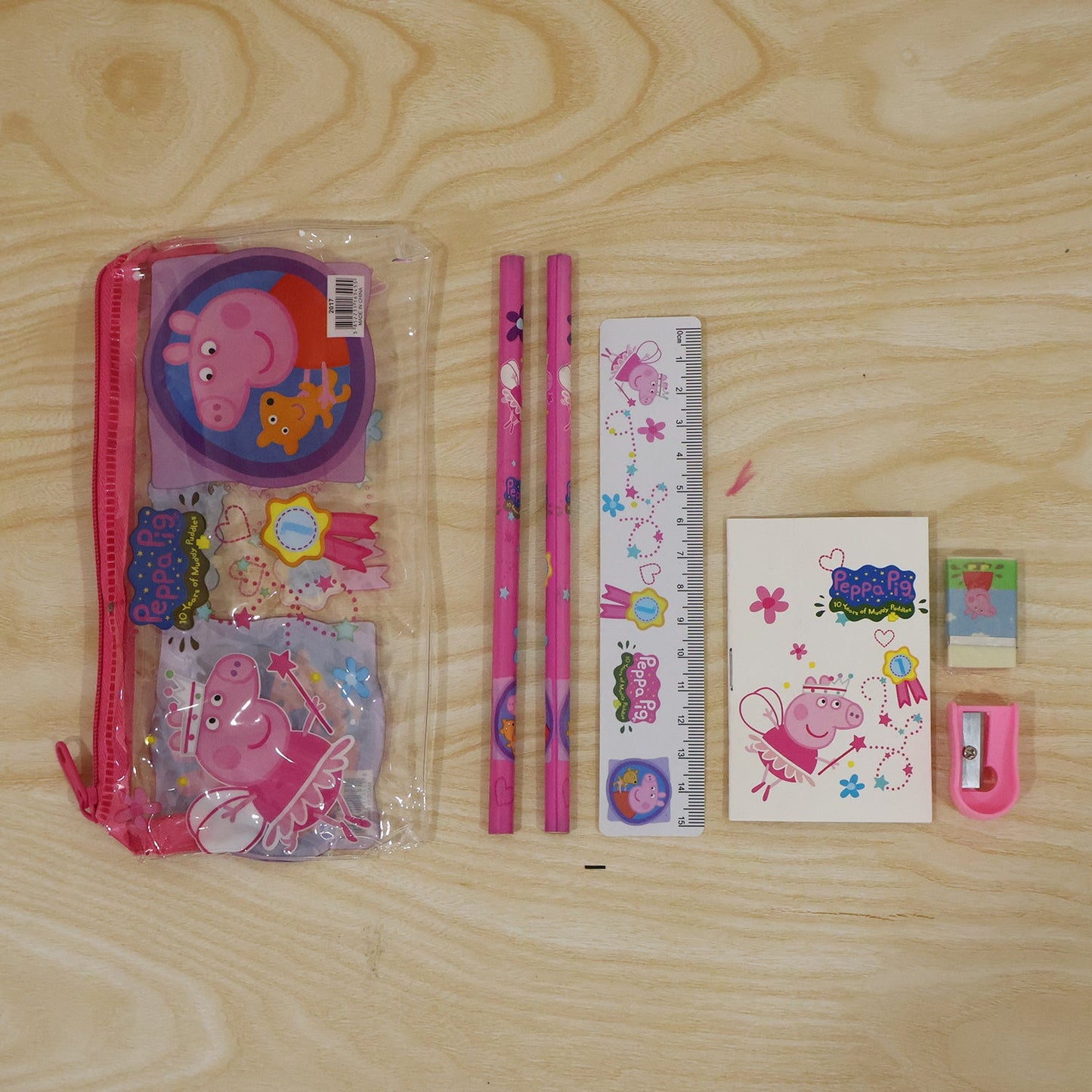 The Peppa Pig stationery set laid out on a light wooden surface, including the clear pink zippered pouch.