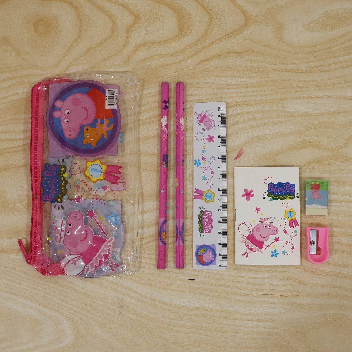 The Peppa Pig stationery set laid out on a light wooden surface, including the clear pink zippered pouch.