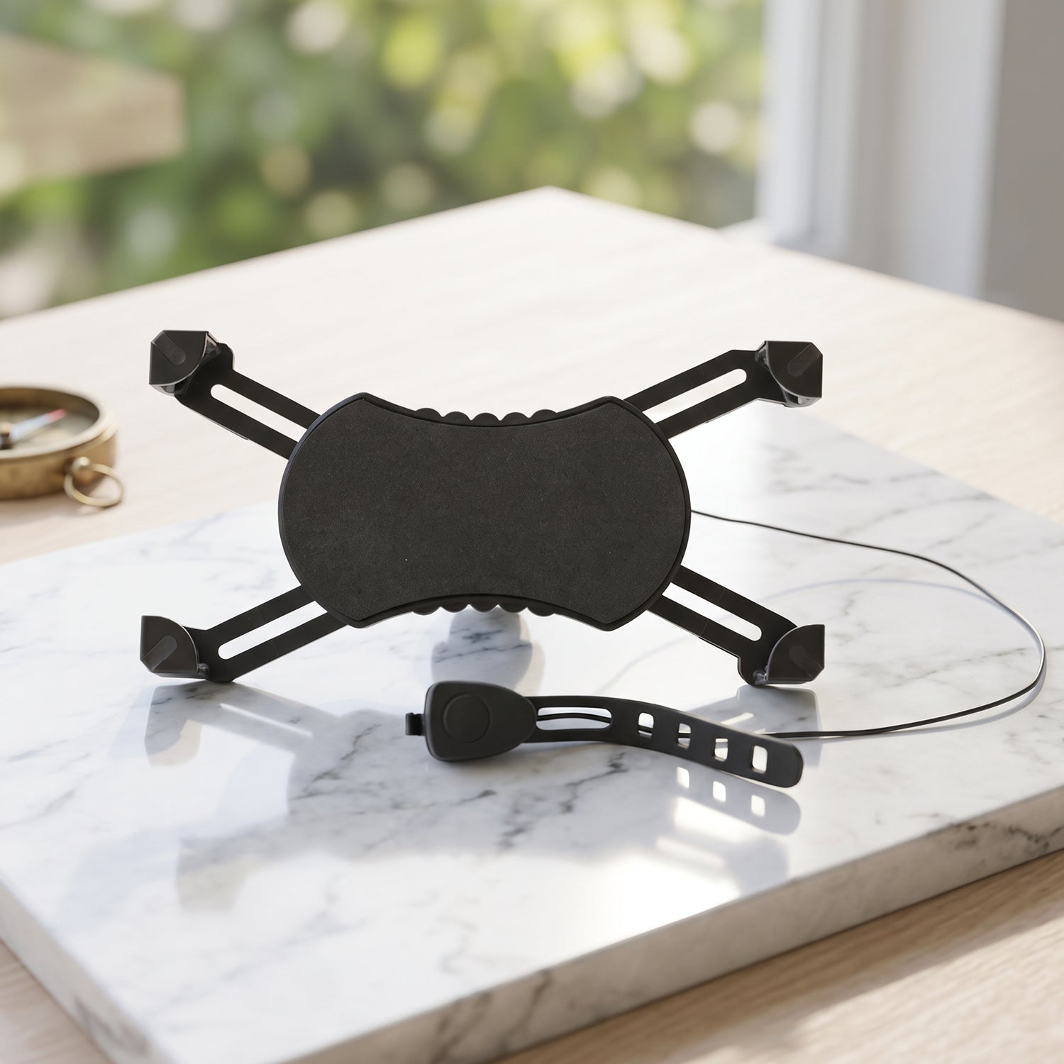 A black bicycle phone holder with an X-shaped back and a separate horn are on a white marble surface.