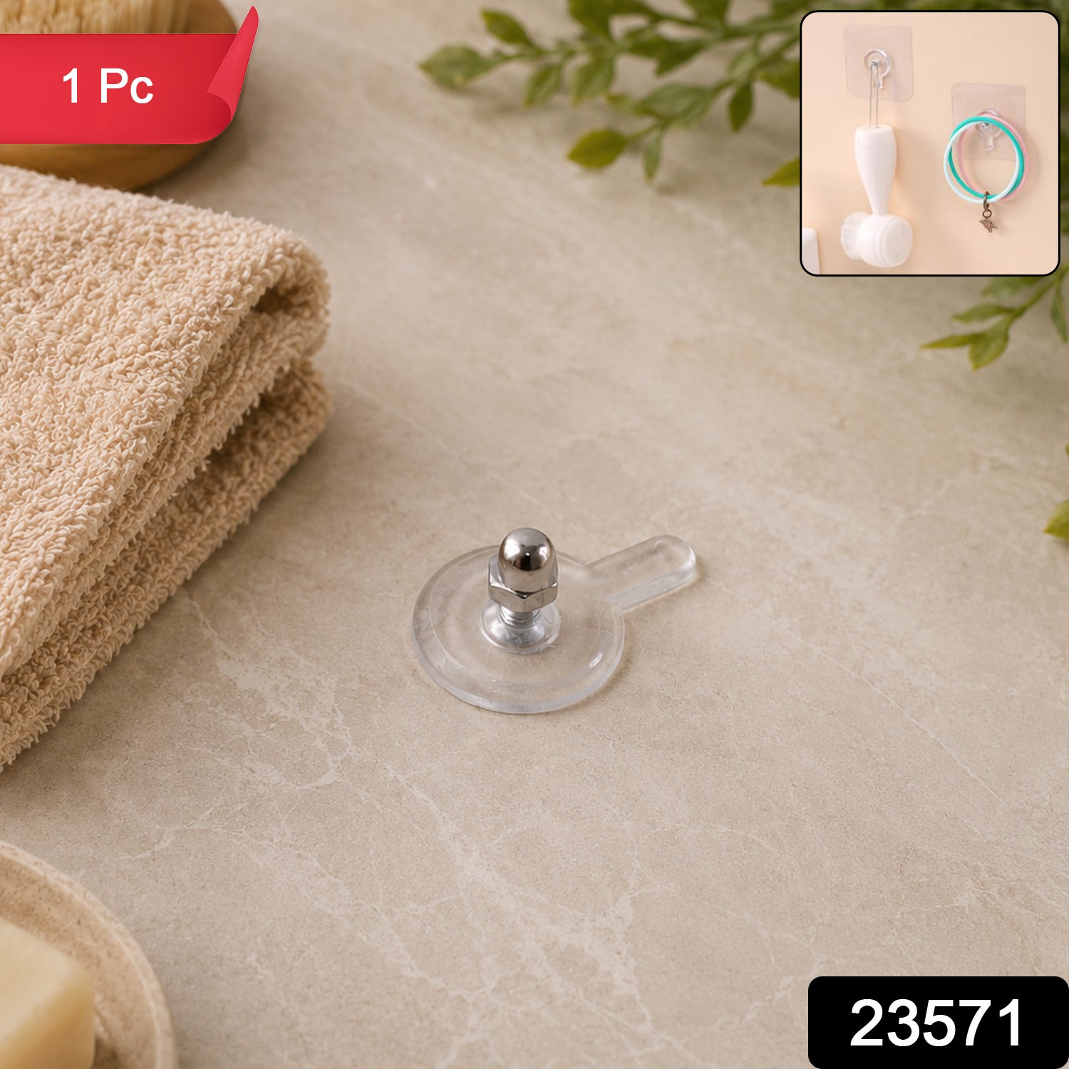 A single clear self-adhesive wall hook with a silver knob sits on a light-colored surface next to a folded towel.