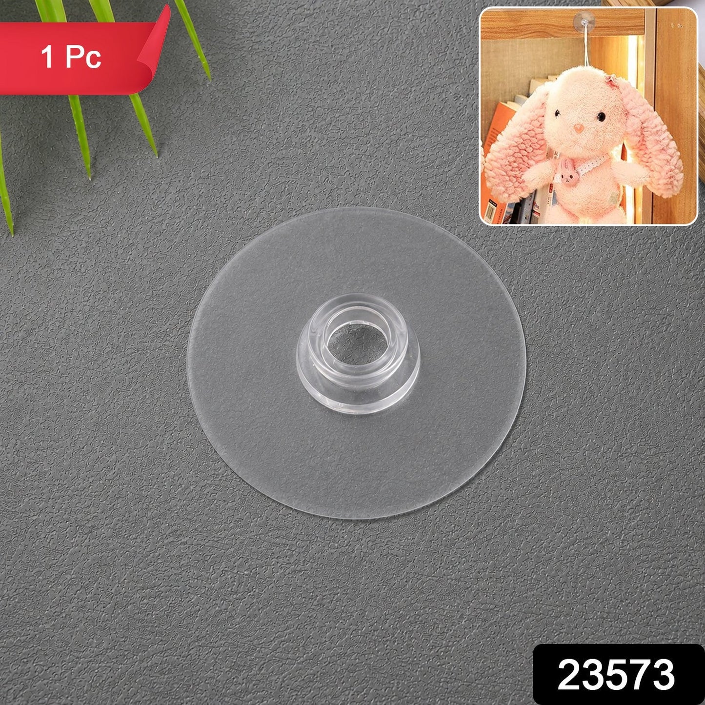 A single clear plastic suction cup hook is centered on a dark grey textured surface, with a small inset showing a plush