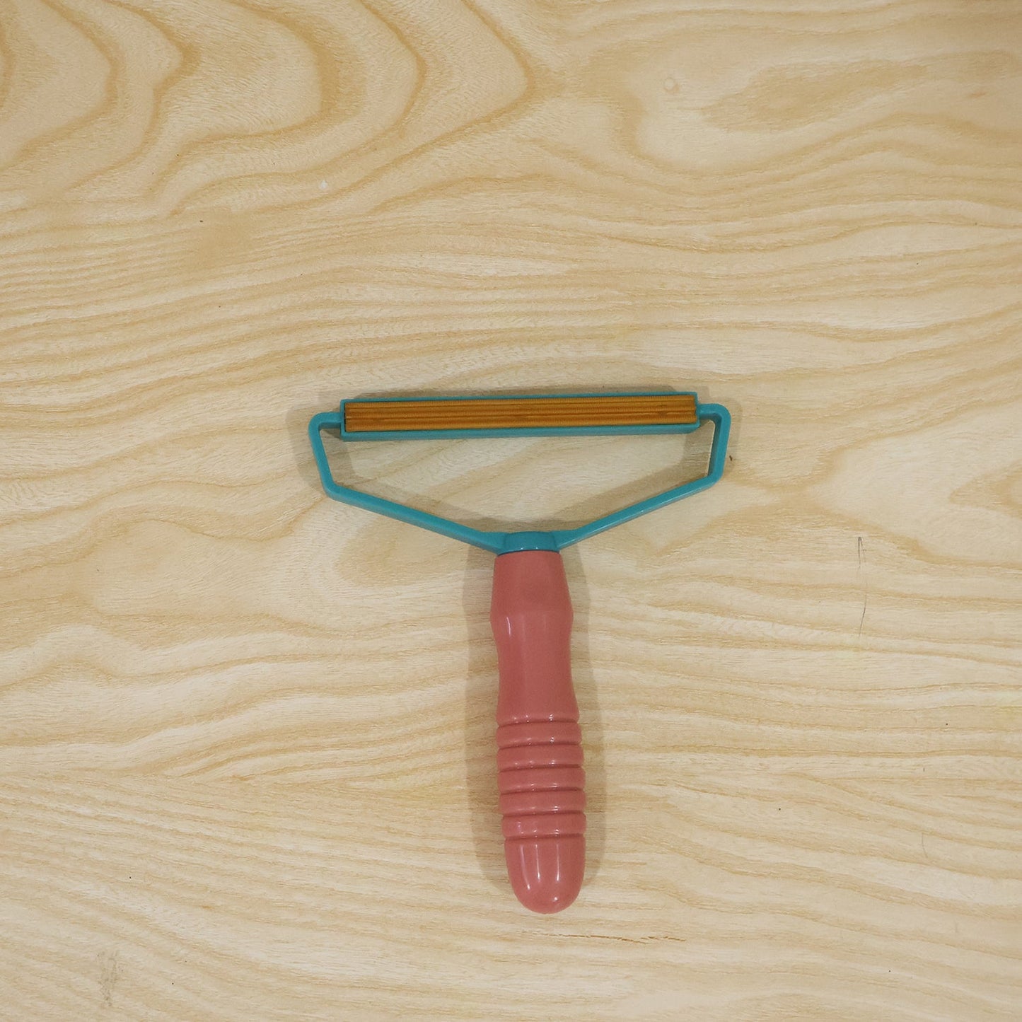 Pink and blue lint remover with textured handle for removing pet hair and lint from fabric.