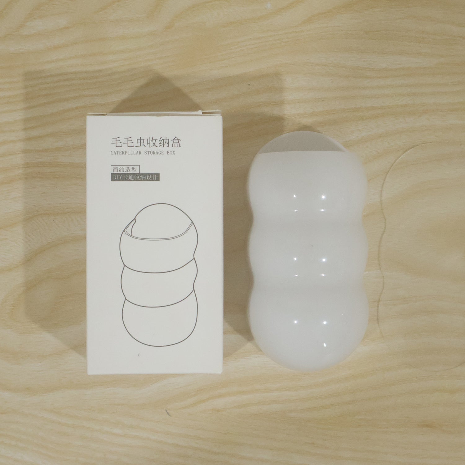 White, caterpillar-shaped holder next to its white packaging box with Chinese text and a line drawing.