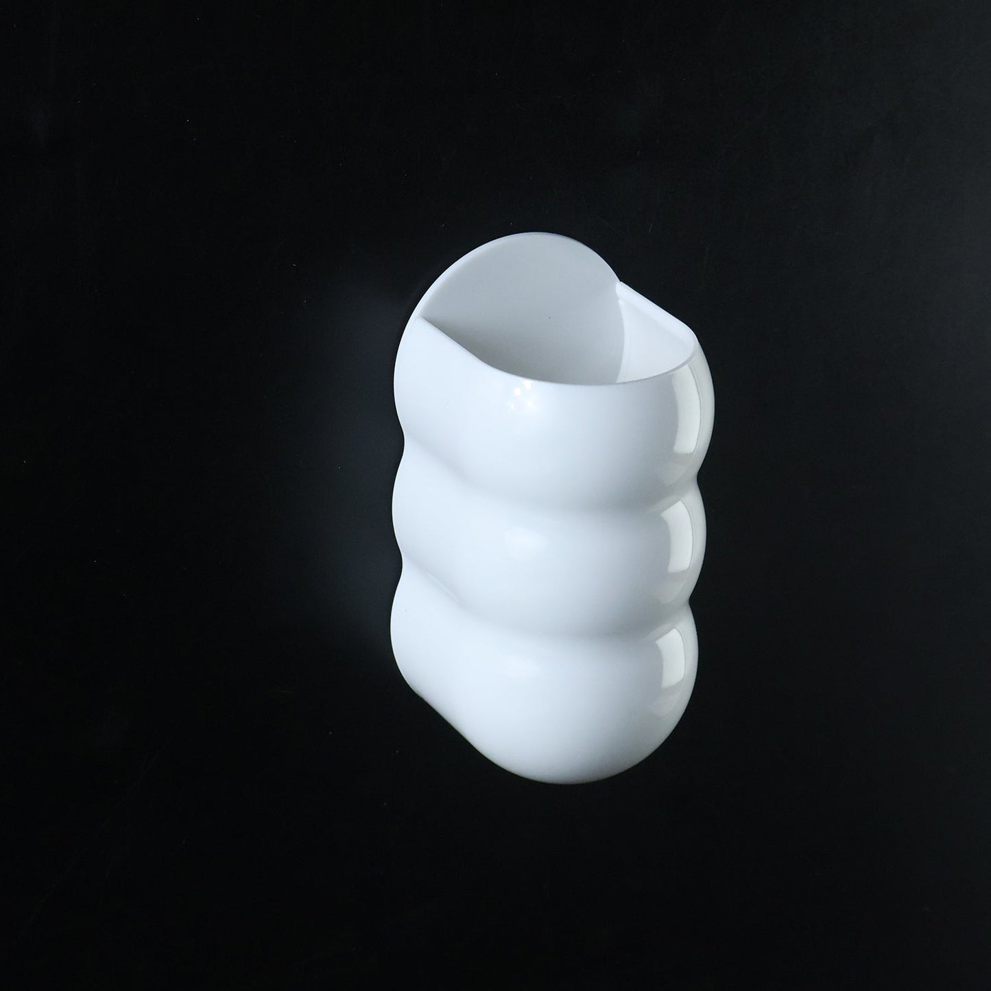 White, caterpillar-shaped wall holder against a solid black background.