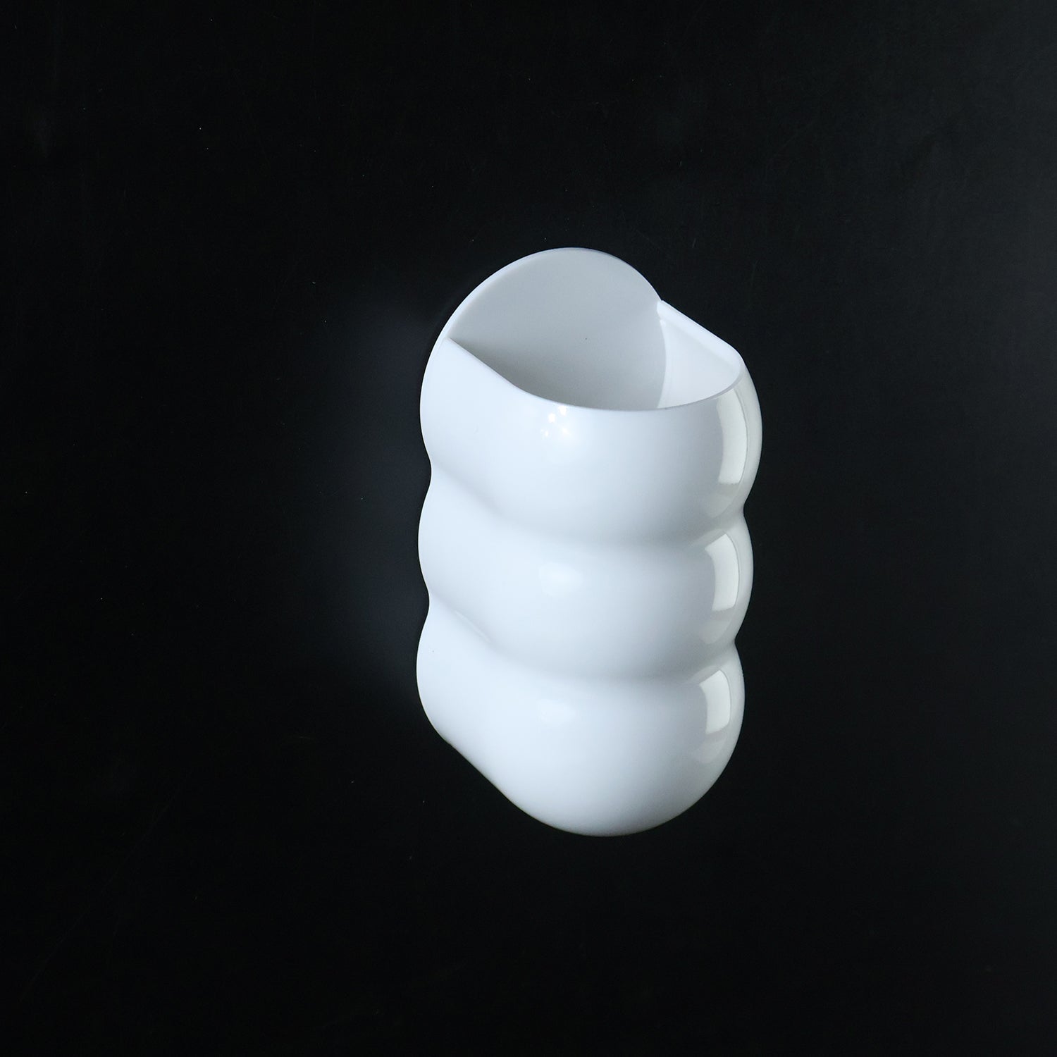 White, caterpillar-shaped wall holder against a solid black background.