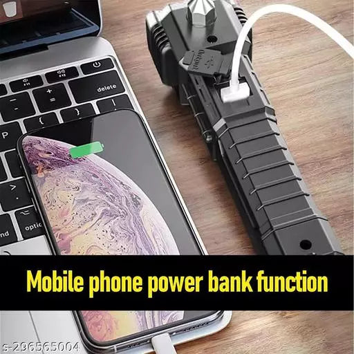 Close-up of the multi-tool flashlight charging a smartphone next to a laptop on a wooden surface.
