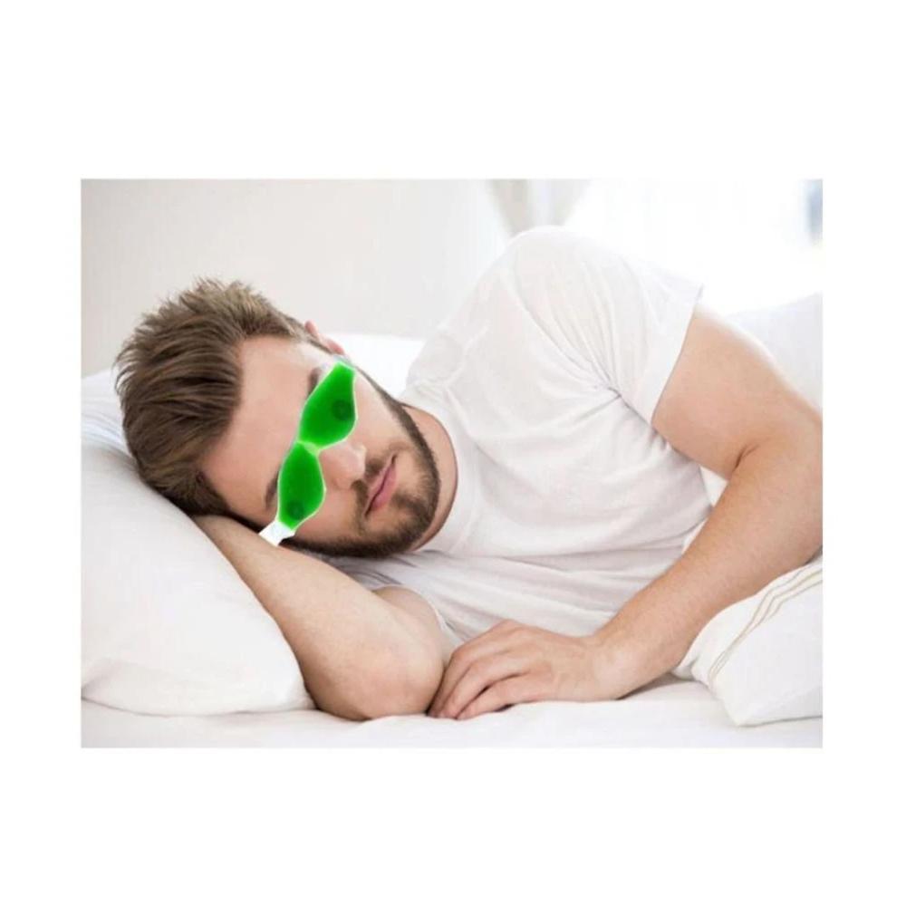 A man with a beard sleeps on a white pillow, wearing a green gel eye mask.