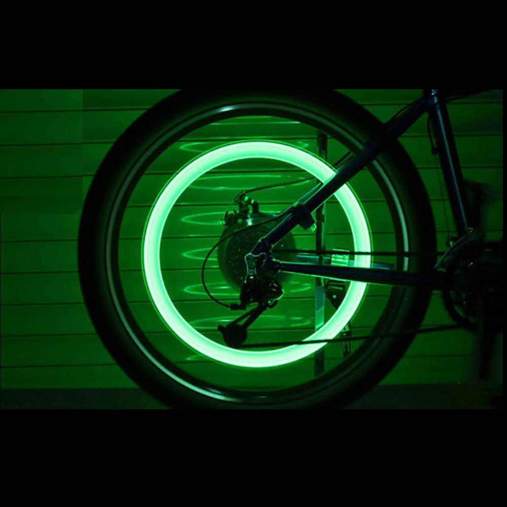 A bicycle wheel with a bright green glowing ring, viewed from the side in a dark setting.