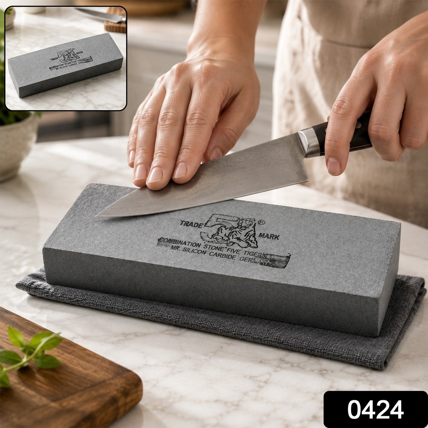A gray silicon carbide whetstone with black text rests on a gray towel on a white marble counter.
