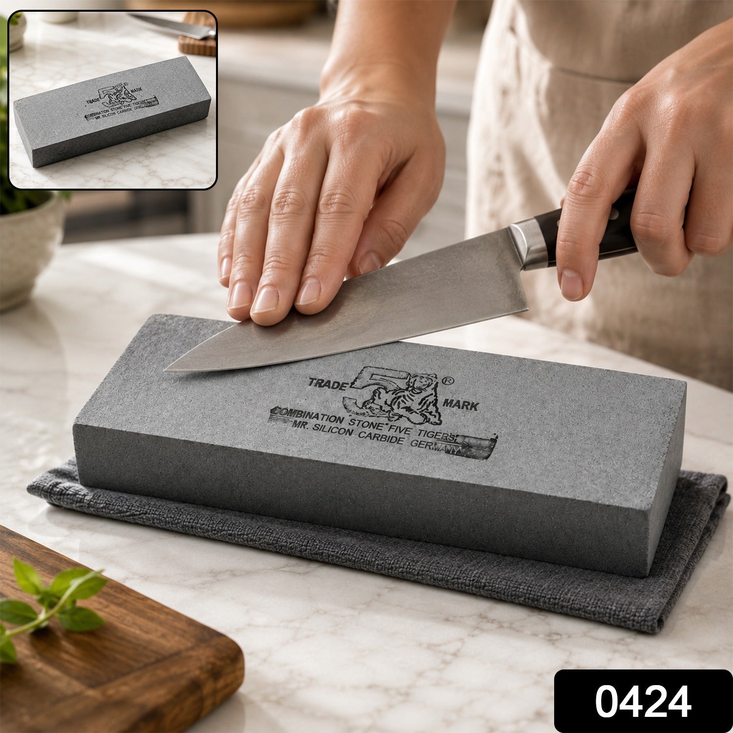 A gray silicon carbide whetstone with black text rests on a gray towel on a white marble counter.