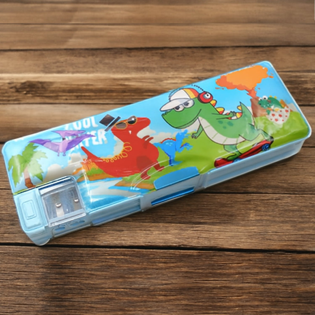 Blue pencil case with cartoon dinosaurs on a wooden table, featuring a built-in pencil sharpener.