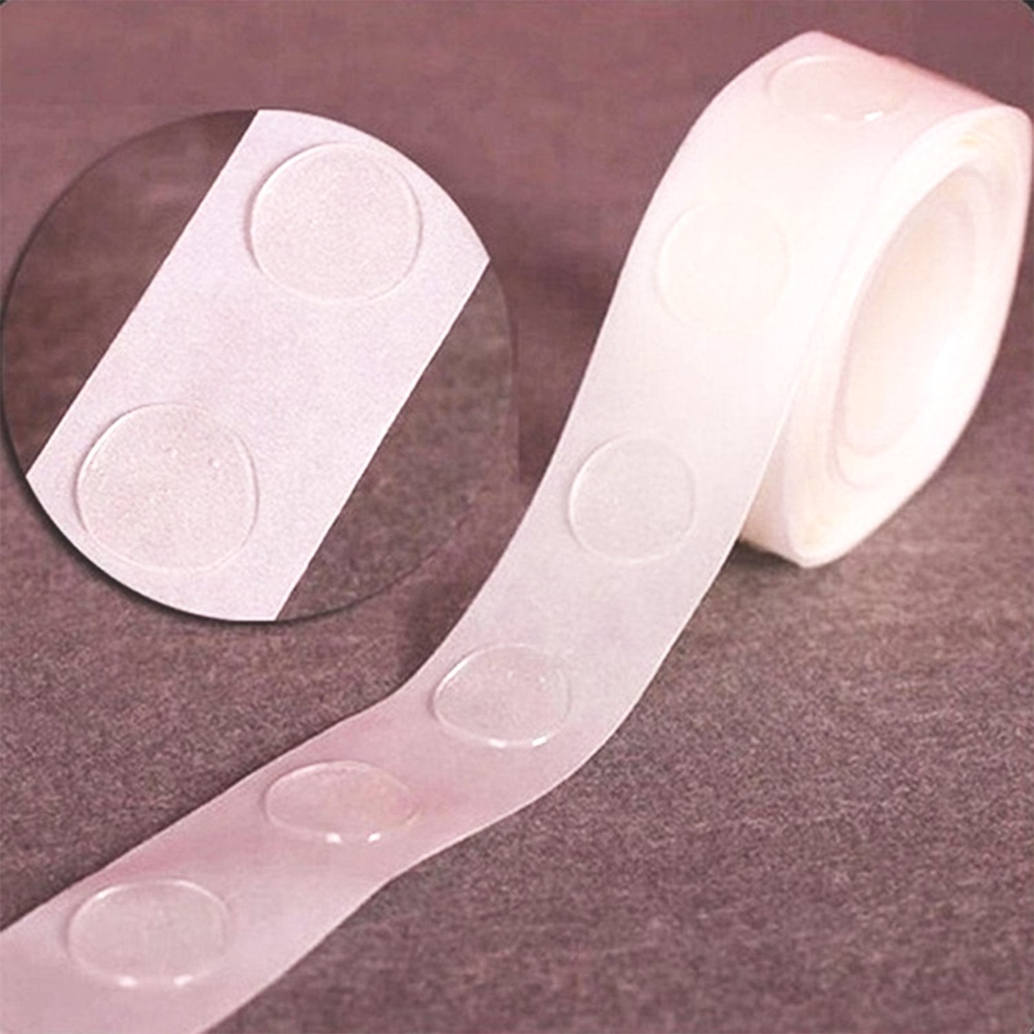 A close-up of a roll of clear, round glue dots on a white paper backing, with a magnified view in a circular inset.