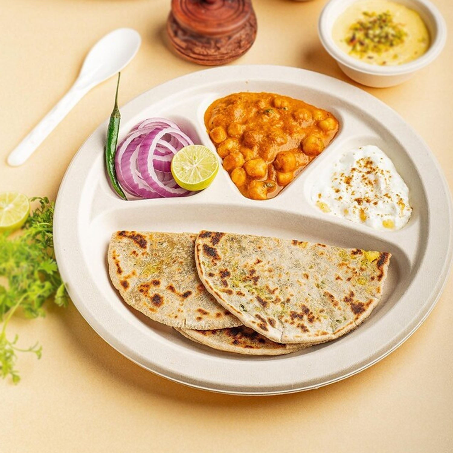 Disposable 4 compartment meal serving plate holding snacks and main course