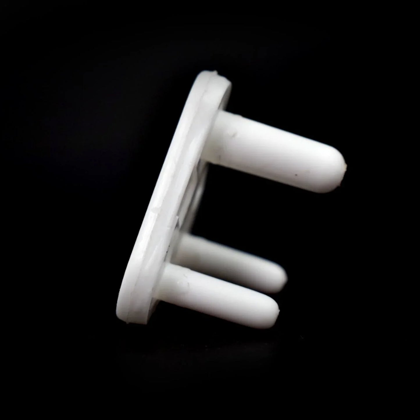 A white 3-pin socket cover is angled against a black background, highlighting its smooth plastic texture.