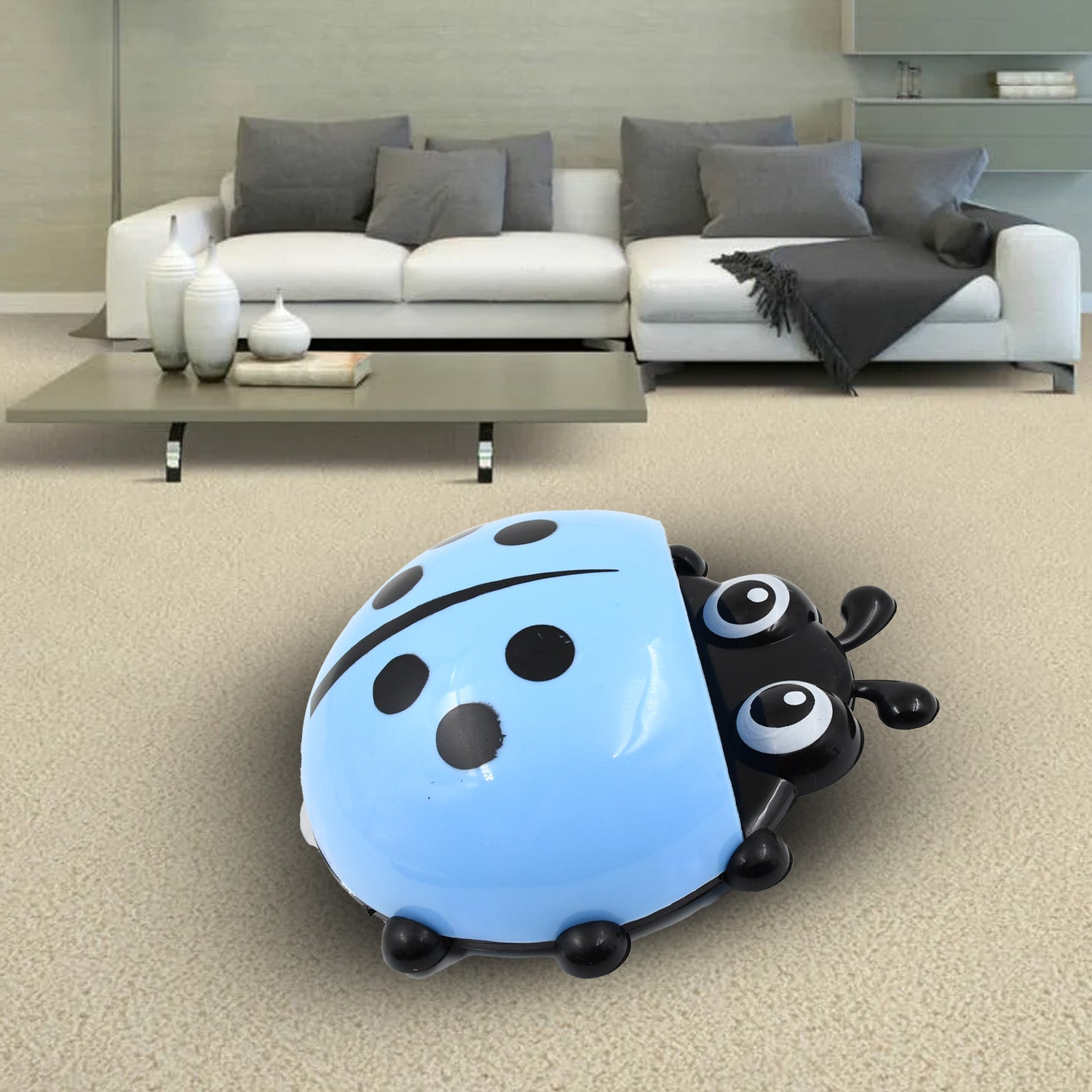 A blue ladybug holder is placed on a beige carpet in a living room setting with a white sofa and coffee table.