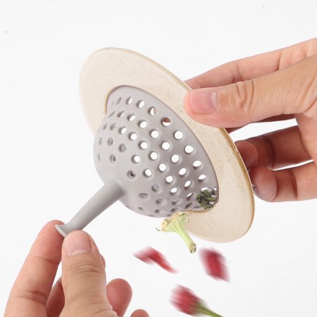 Hands holding a beige and gray silicone sink strainer, inverting it to release red petals and green stems.