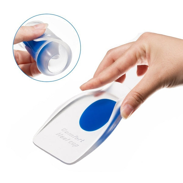 A hand holds a clear gel heel cup with a blue center, with an inset showing the cup being squeezed.