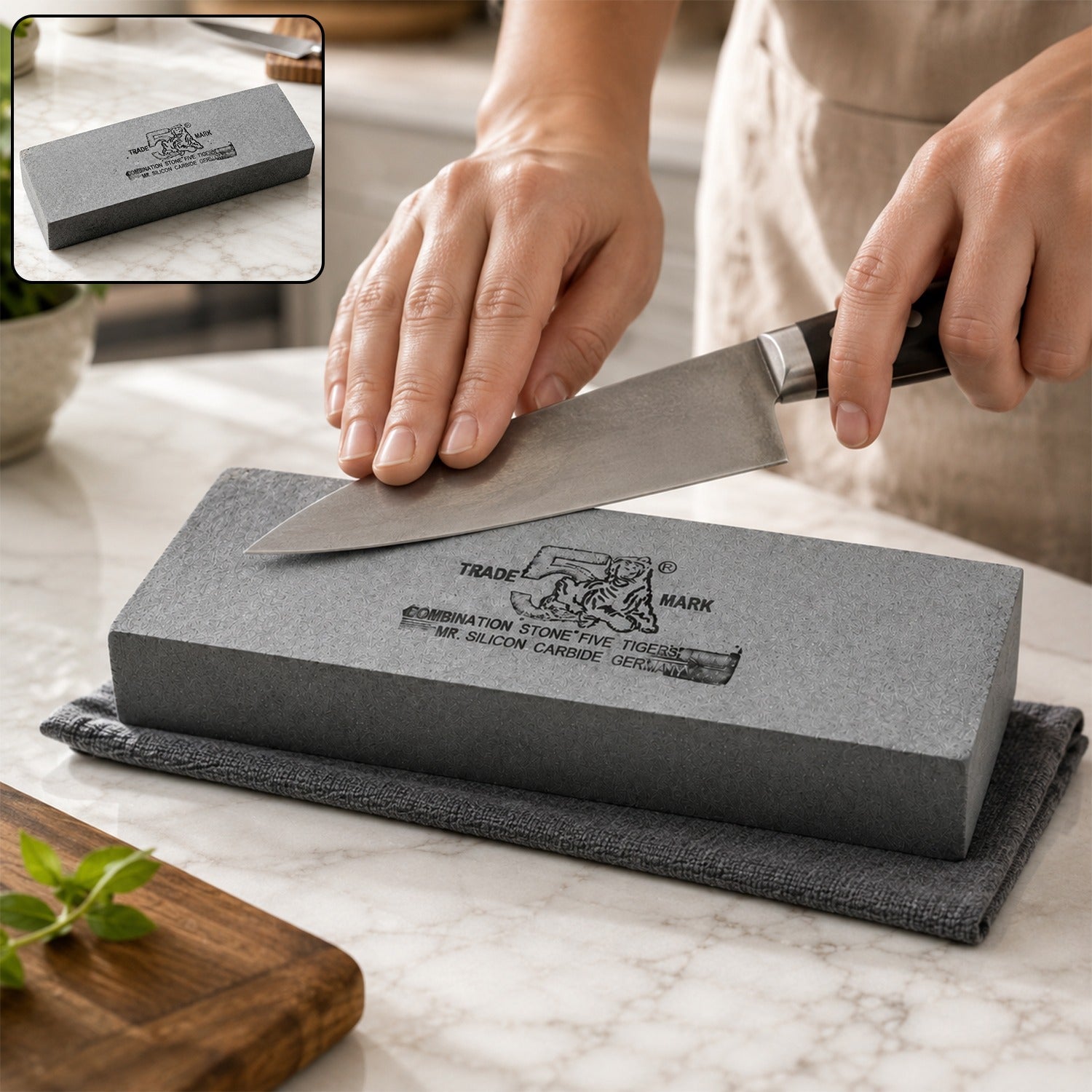 A person's hands sharpen a knife on a gray silicon carbide whetstone, with a small inset showing the stone alone.